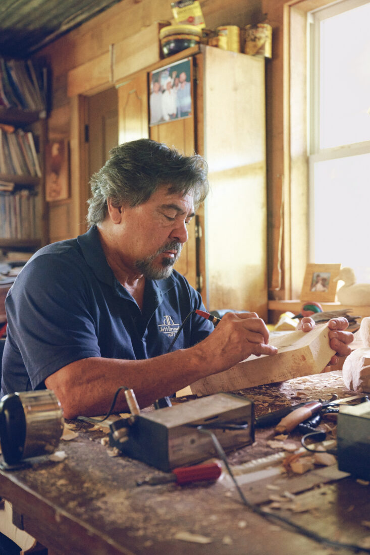 A man carves wood in a studio
