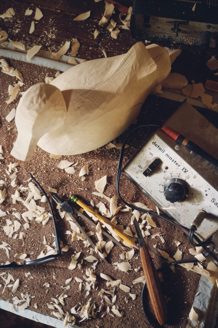 A wood carving of a duck on a work table