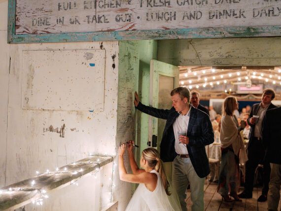 a bride and groom sign a wall