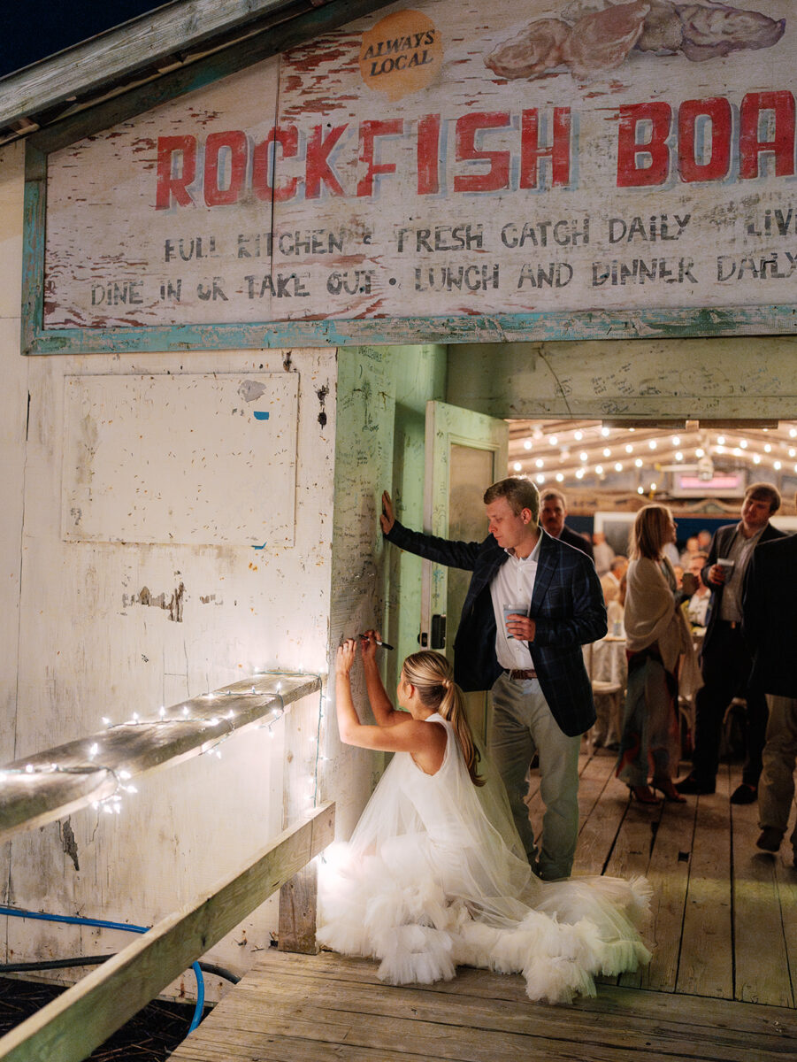 a bride and groom sign a wall