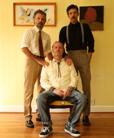 A portrait of three men in a yellow room