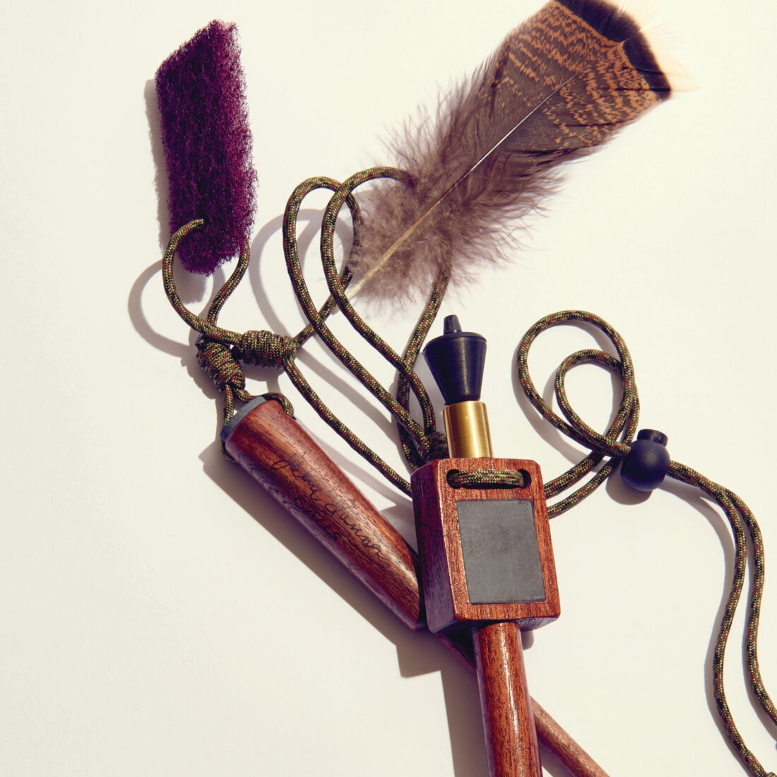 A wood turkey call with a feather