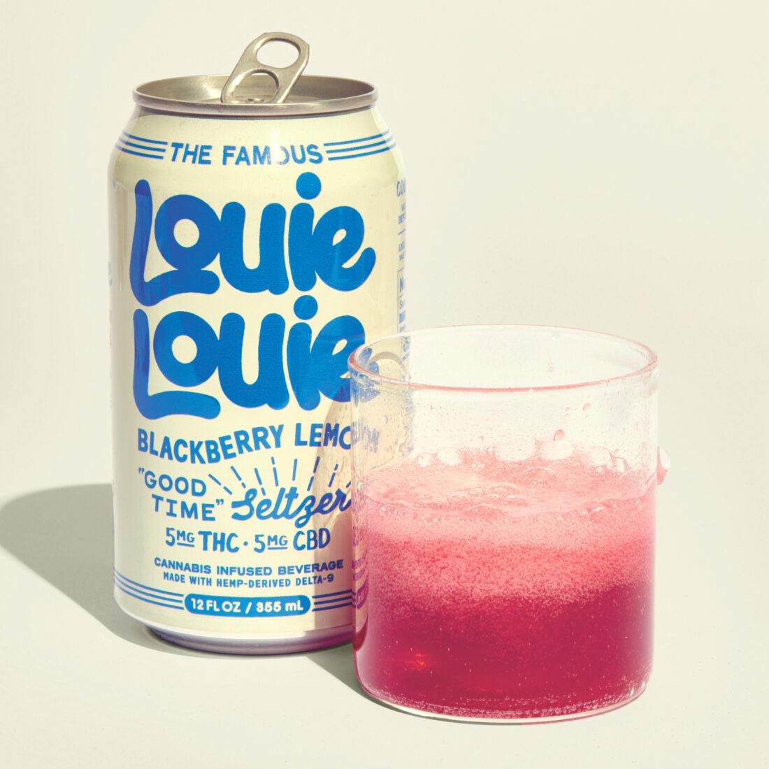 A glass of pink soda and a can