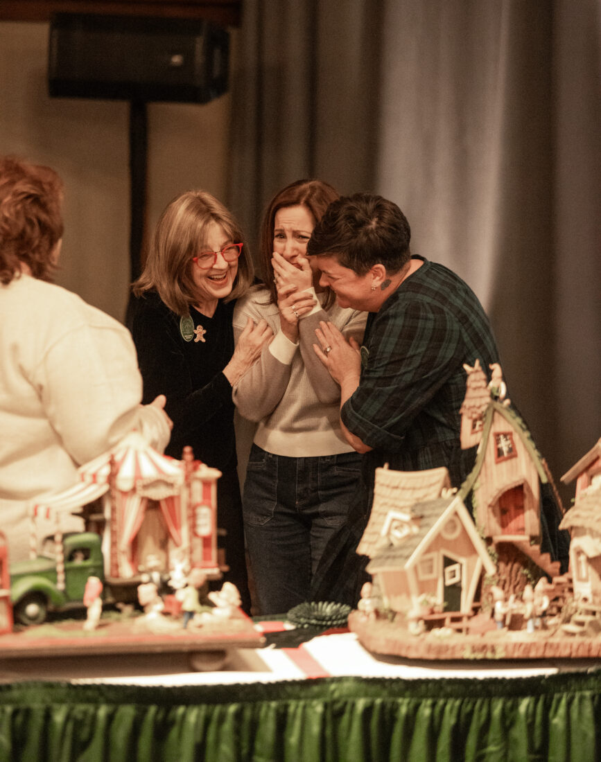 A woman gasps at a gingerbread house competition