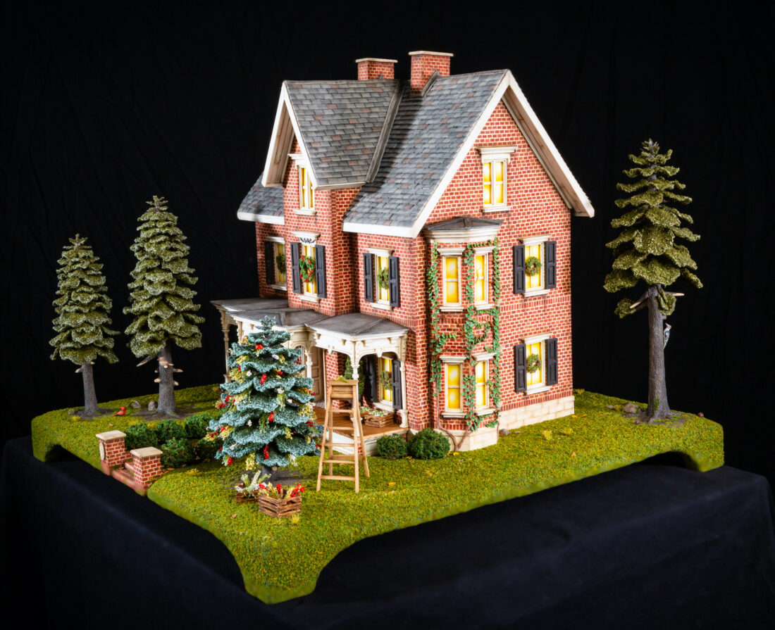 A gingerbread house of a brick house with a Christmas tree