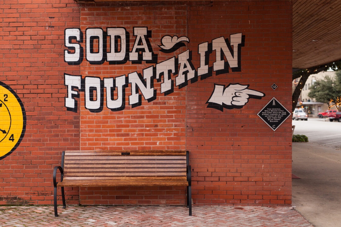A brick wall with soda fountain lettering painted on it
