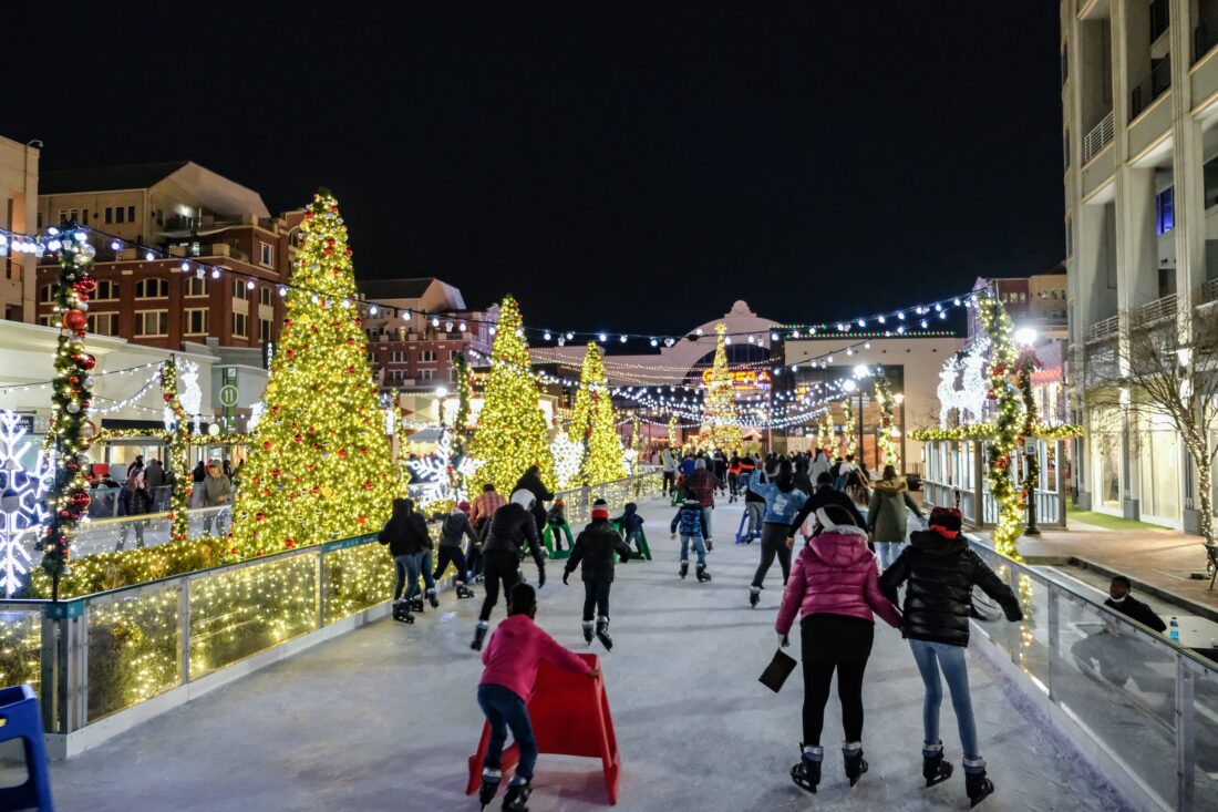 an ice skating rink around Christmas trees at night