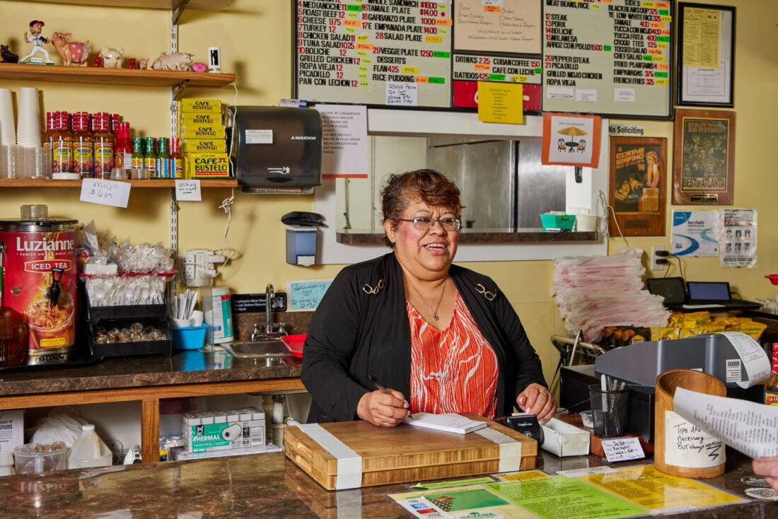 A woman stands behind a restaurant counter