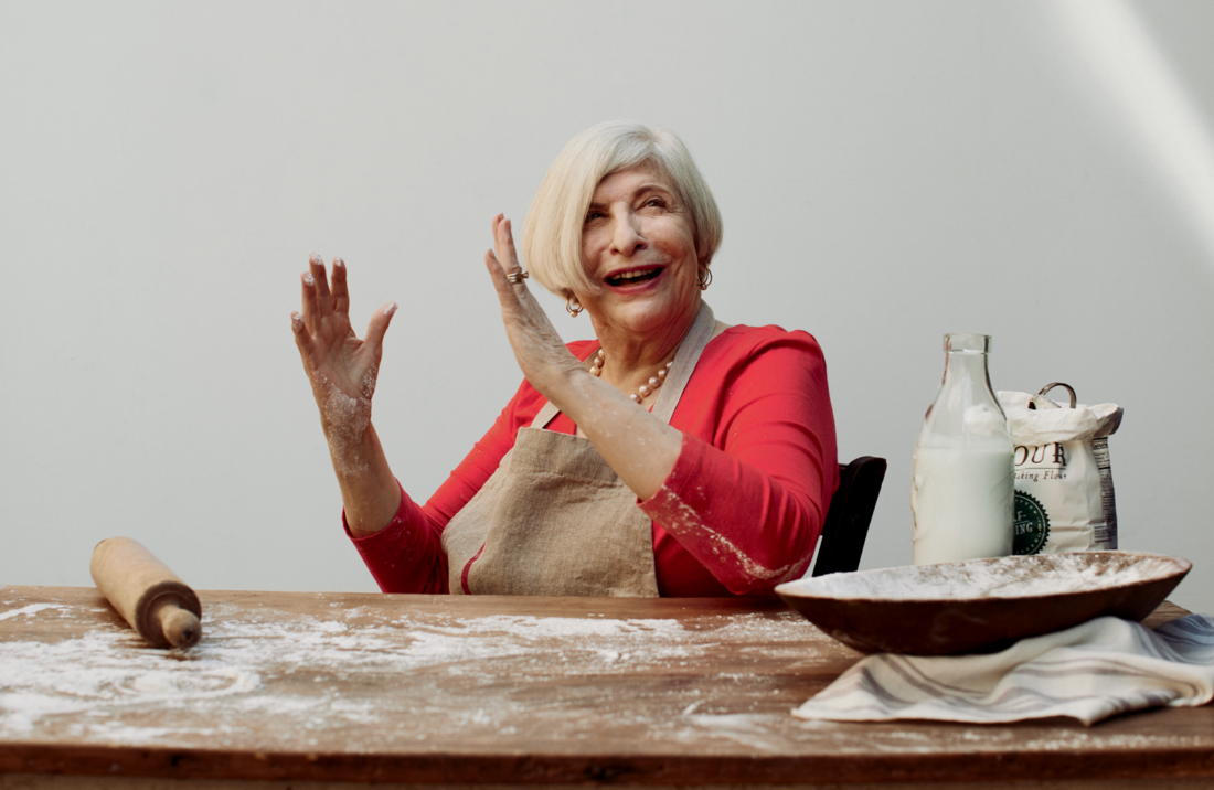 A portrait of a woman at a table with a rolling pin