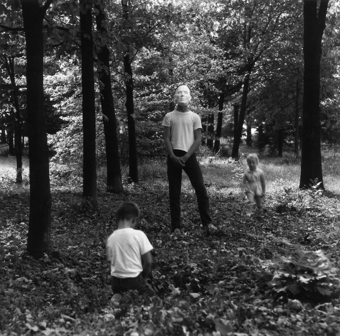 A black and white portrait of a man with a mask with two children
