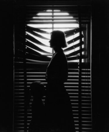 A black and white photo of a woman and child in front of a window