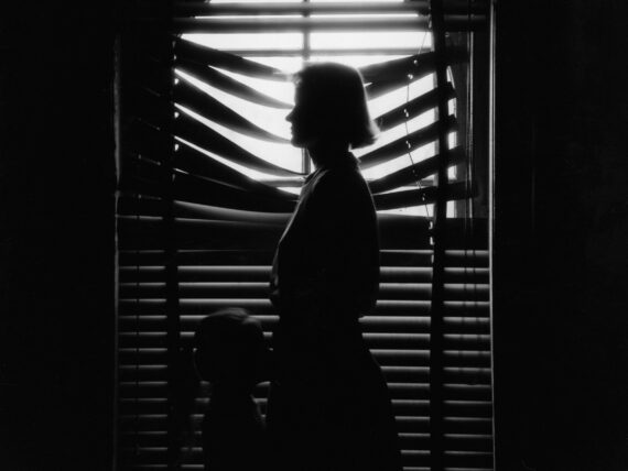 A black and white photo of a woman and child in front of a window
