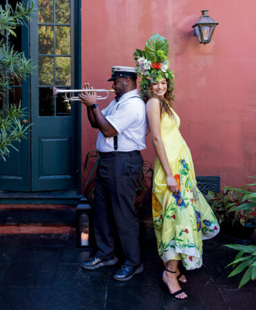 A man playing a trumpet back-to-back with a woman looking at the camera