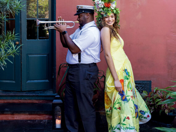 A man playing a trumpet back-to-back with a woman looking at the camera