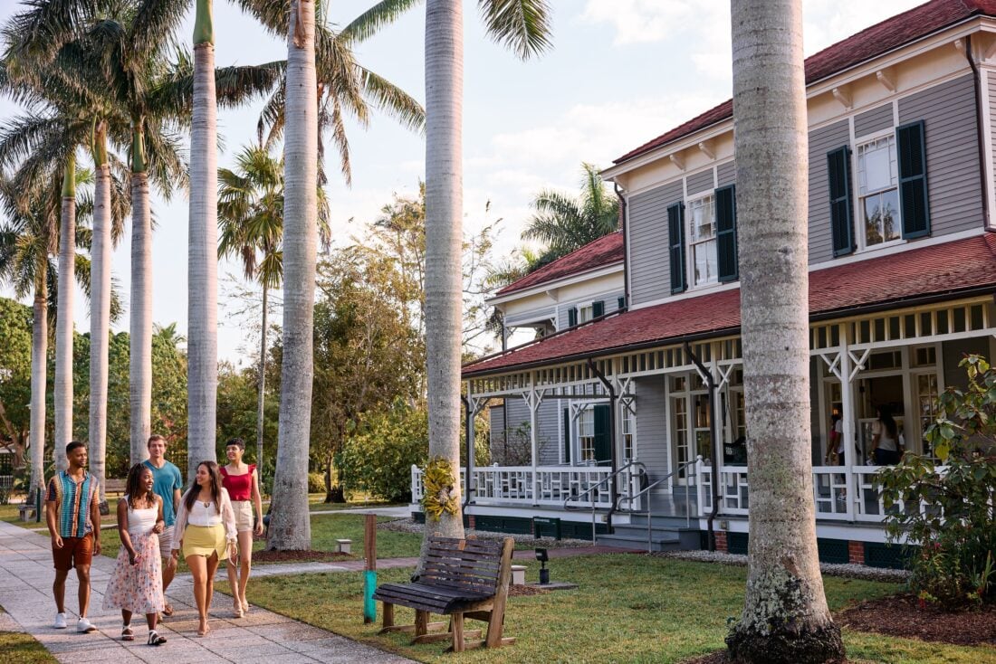 A group of people walk by a historic home