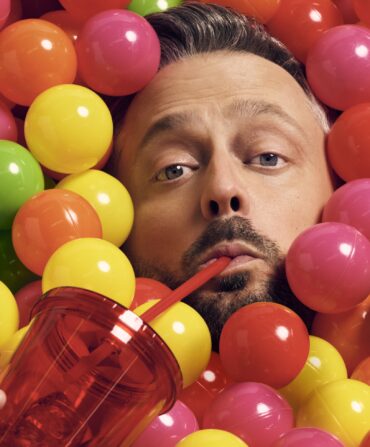 A portrait of Nate Bargartze in a ball pit