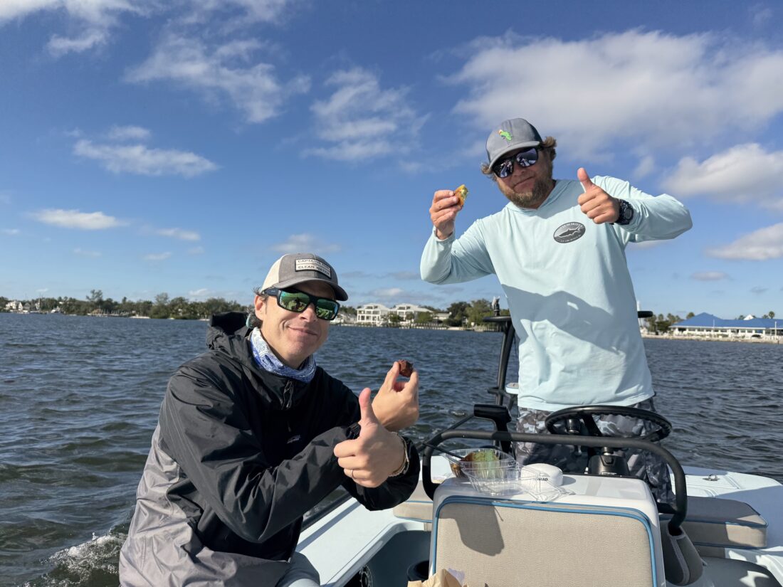 Two men hold bites of cake in a boat