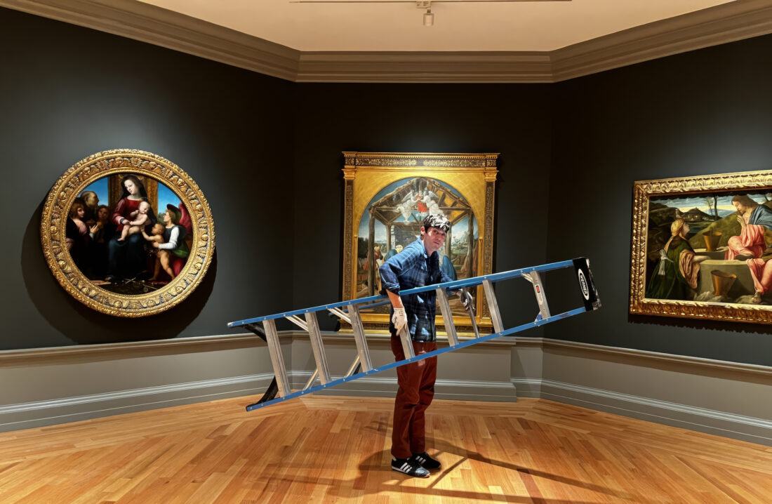 A man holds a ladder in a gallery of art