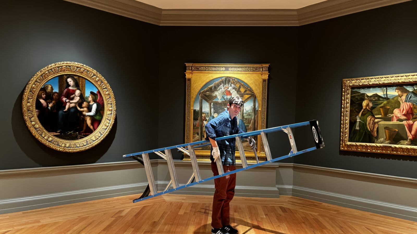 A man holds a ladder in a gallery of art