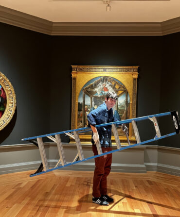A man holds a ladder in a gallery of art