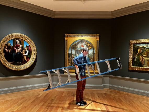 A man holds a ladder in a gallery of art