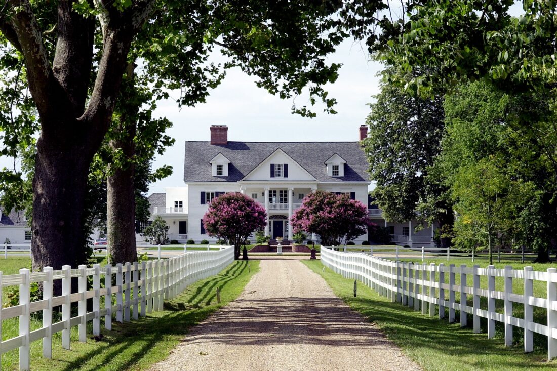 A large white house at the end of a dirt path
