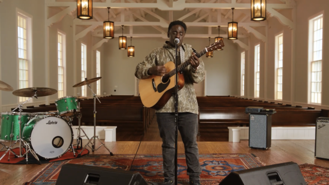 A man on a stage with a guitar