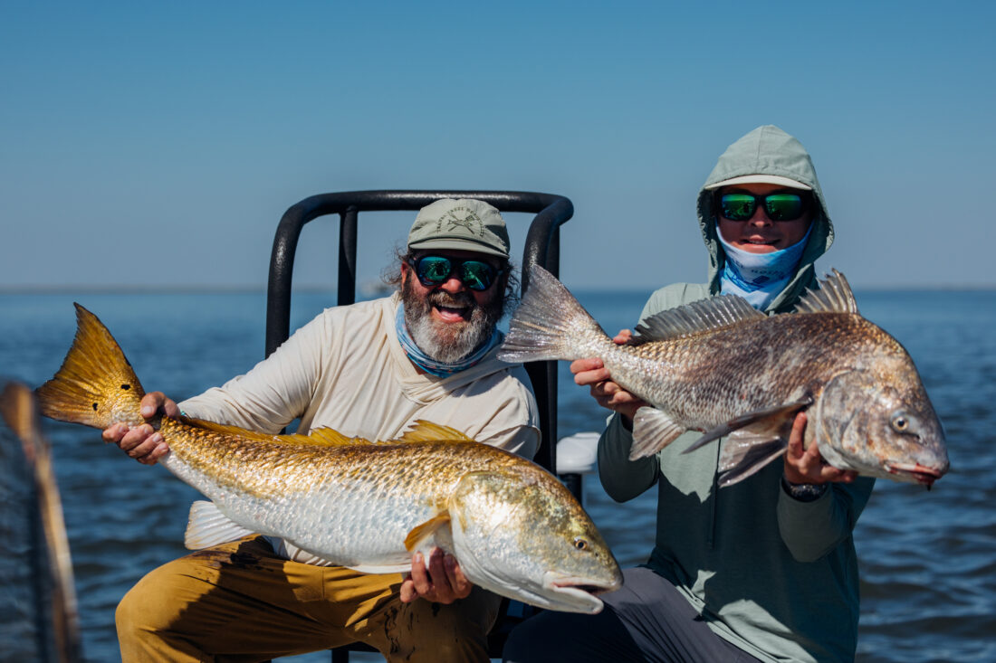 Two people hold up fish