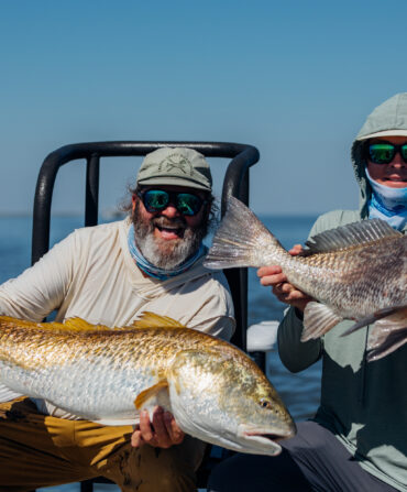 Two people hold up fish