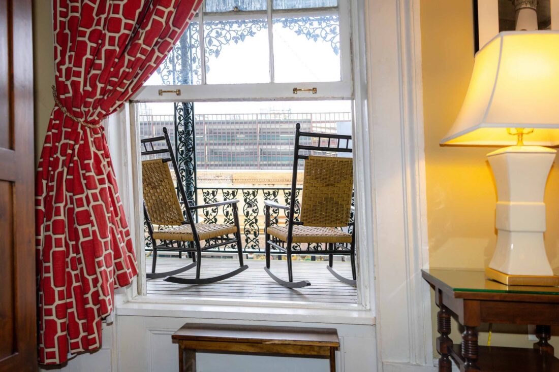 An open window shows a porch with rocking chairs