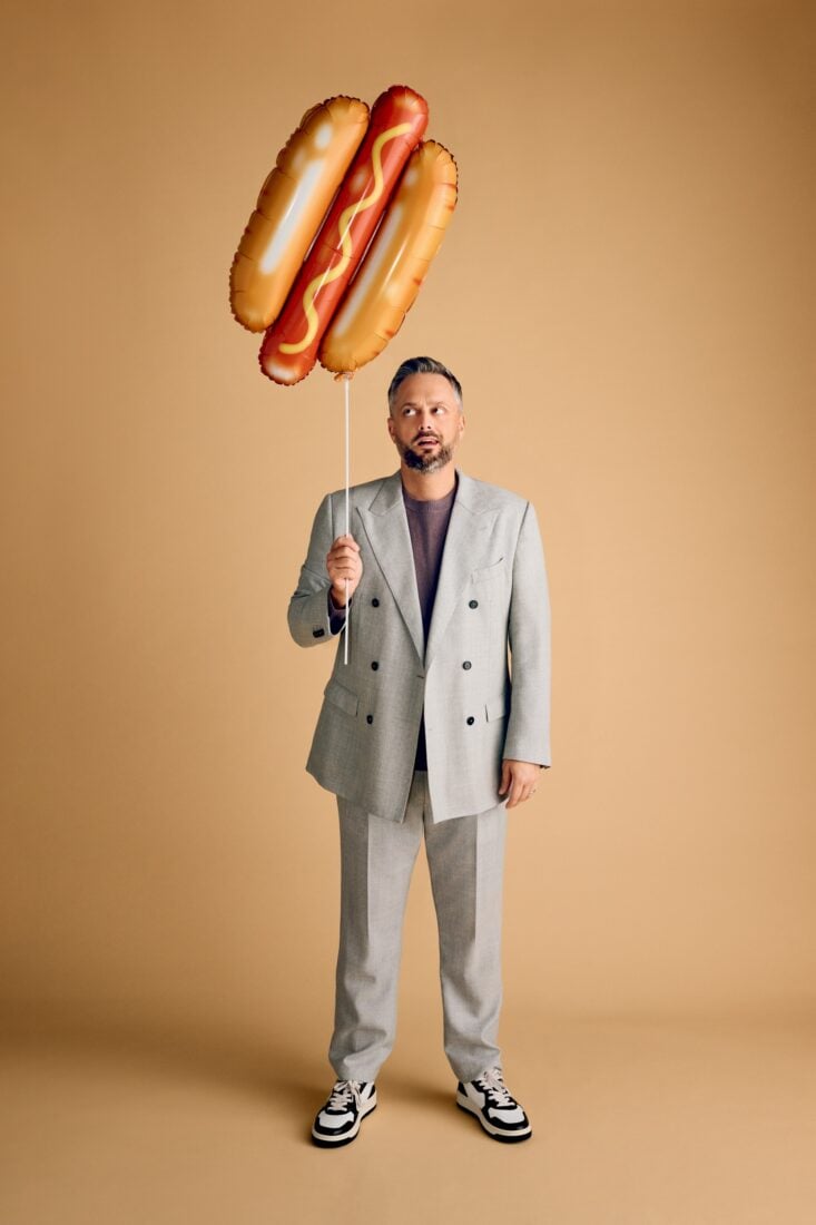A portrait of Nate Bargartze holding a hot dog balloon
