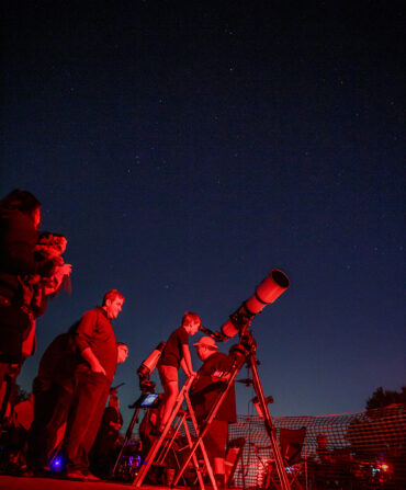 A child looks through a telescope at night