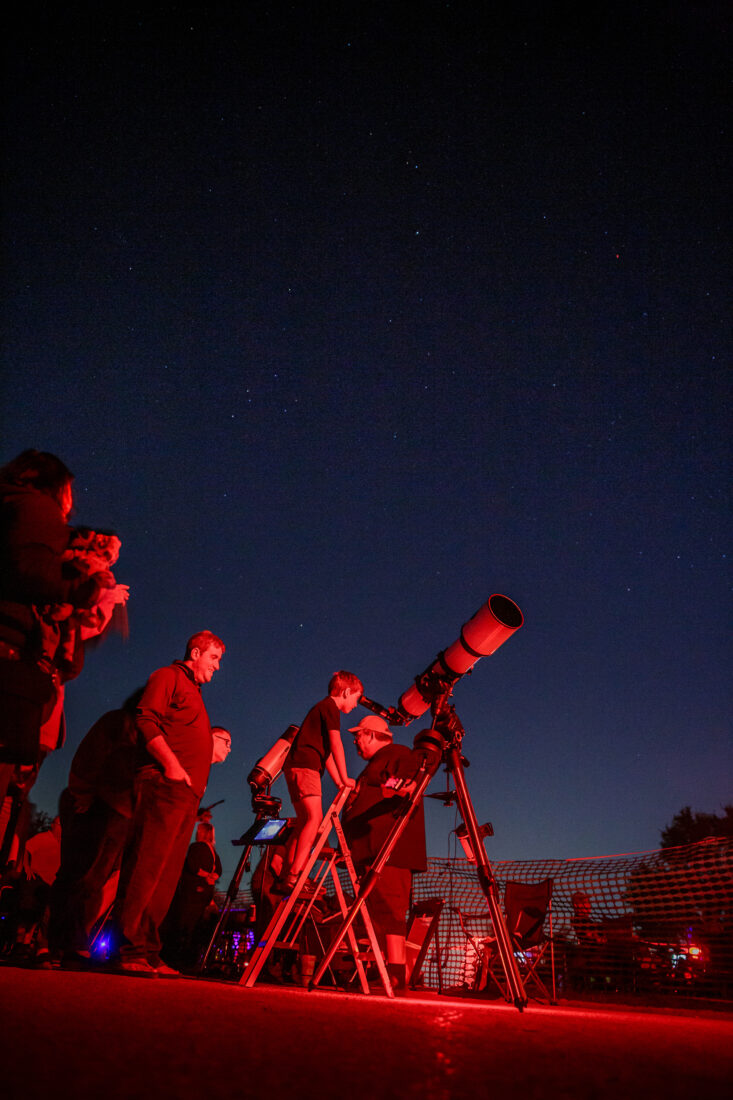 A child looks through a telescope at night