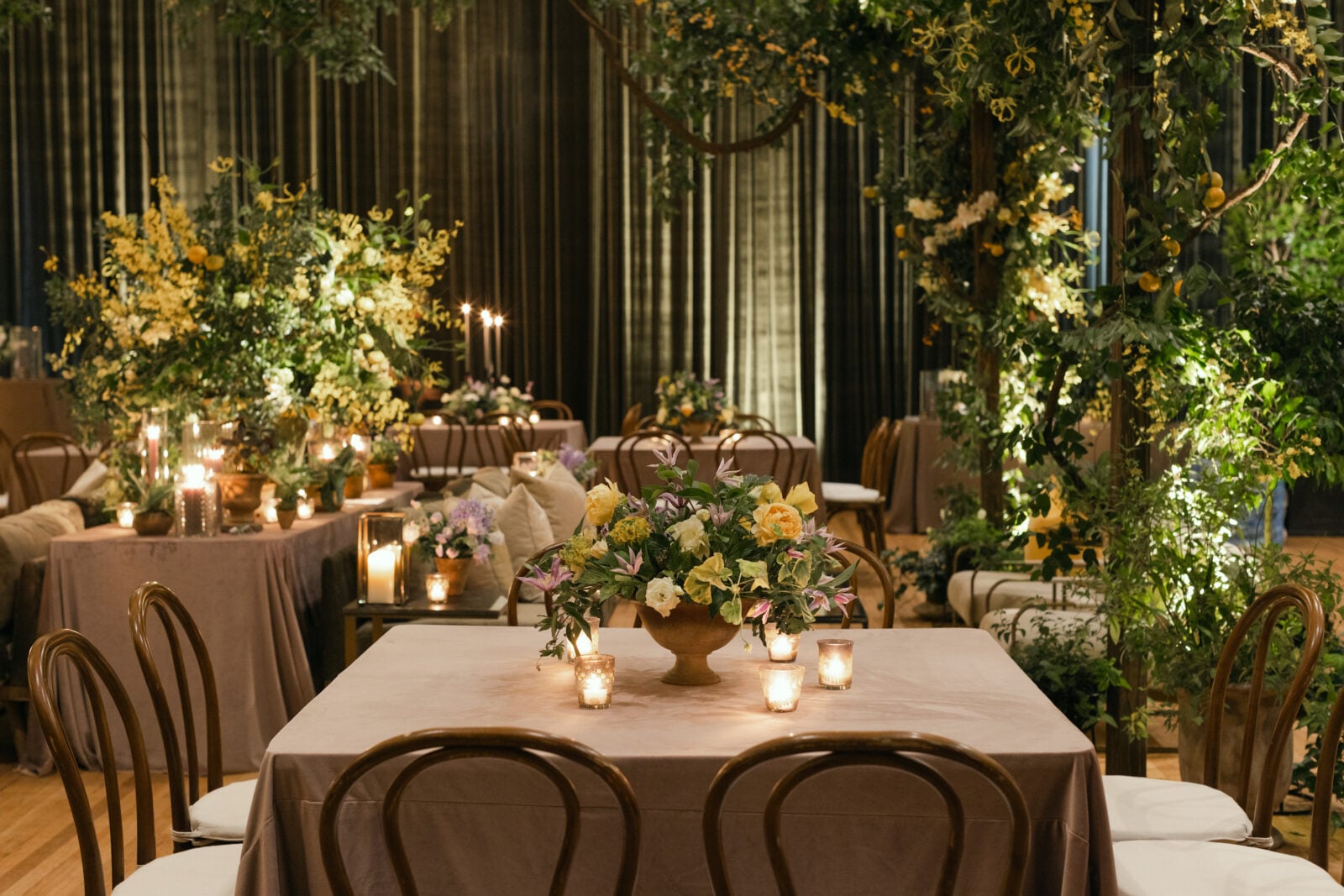 Terra-cotta vessels full of clematis, hellebores, ranunculus, garden roses, and geranium greenery adorned tables.