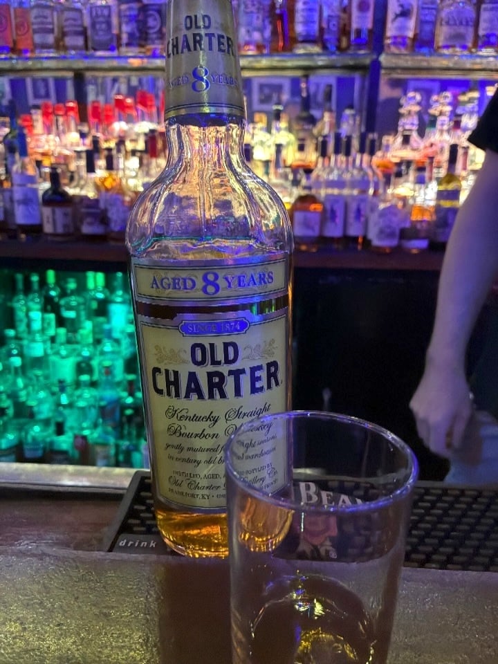 A cup and bottle of bourbon at a dive bar