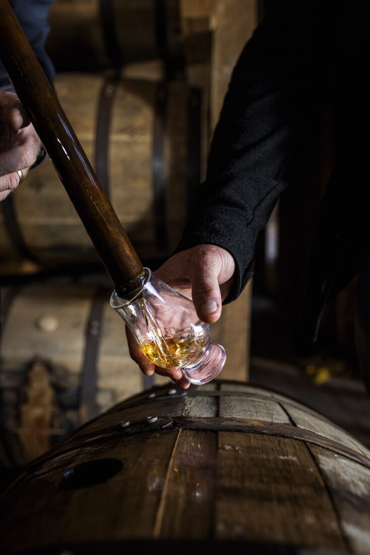 Sampling bourbon from a barrel.