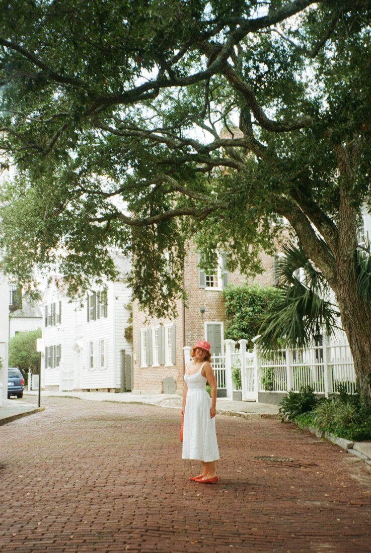 A woman stands on a brick road under trees