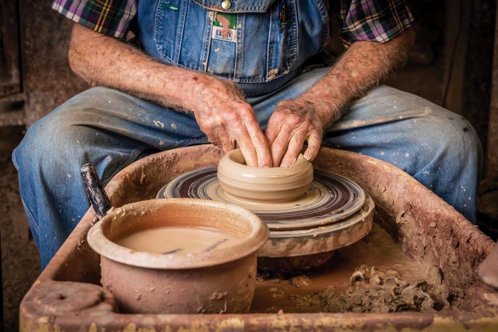 A man turns pottery on a wheel