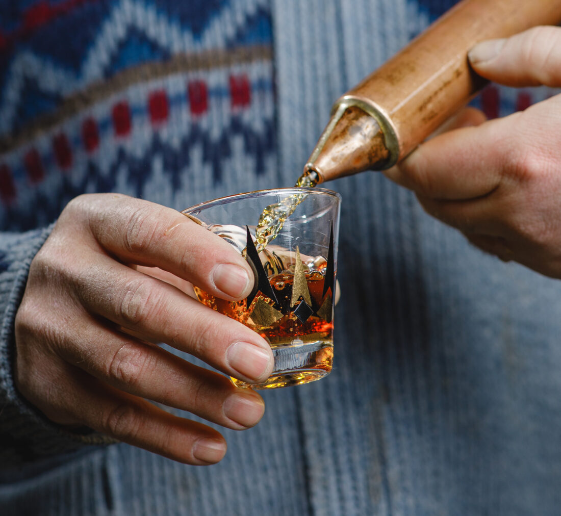 A man holds a shot of bourbon