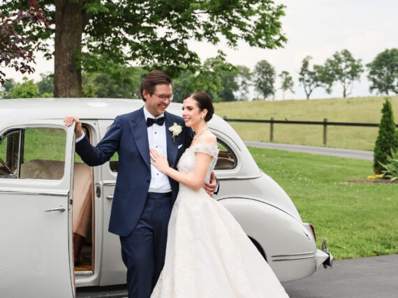 A wedding couple by a car