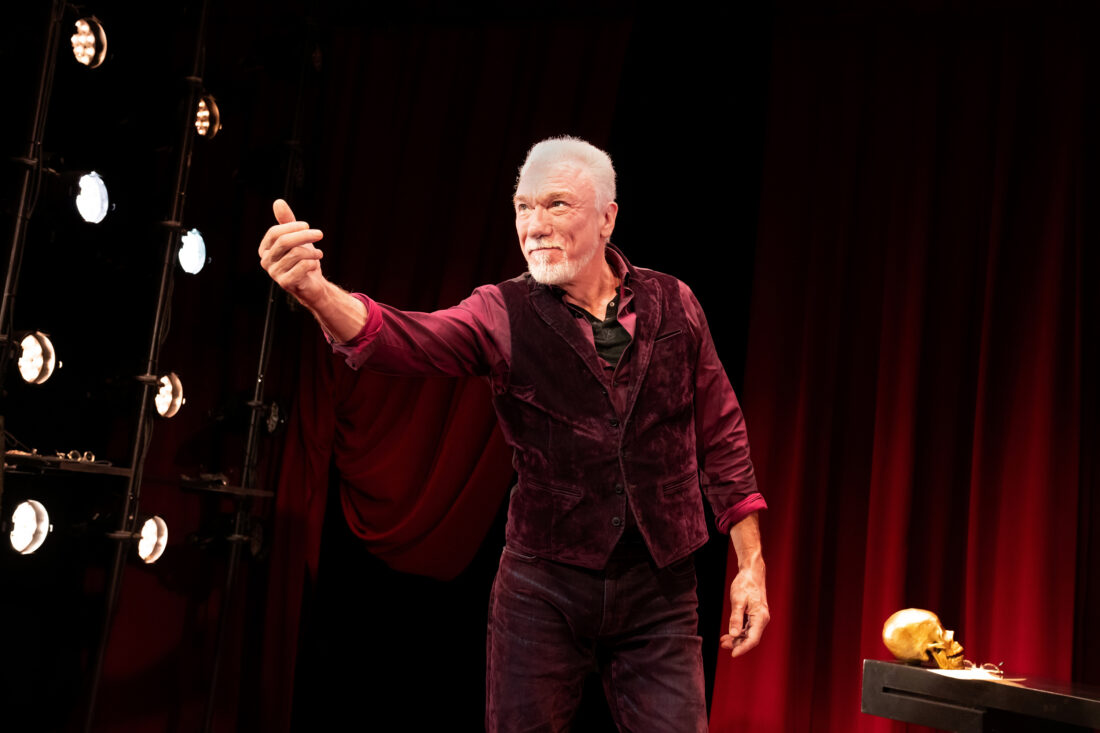 image of Patrick Page on stage against a red back drop