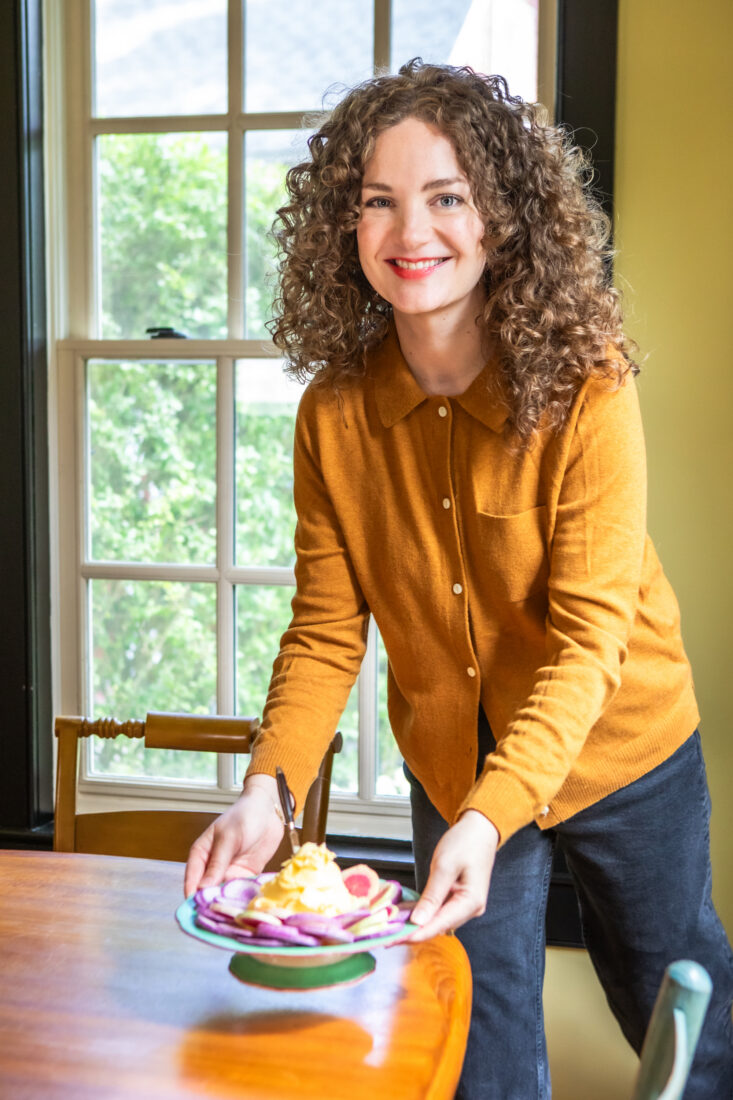 A woman puts a plate of radishes on a table