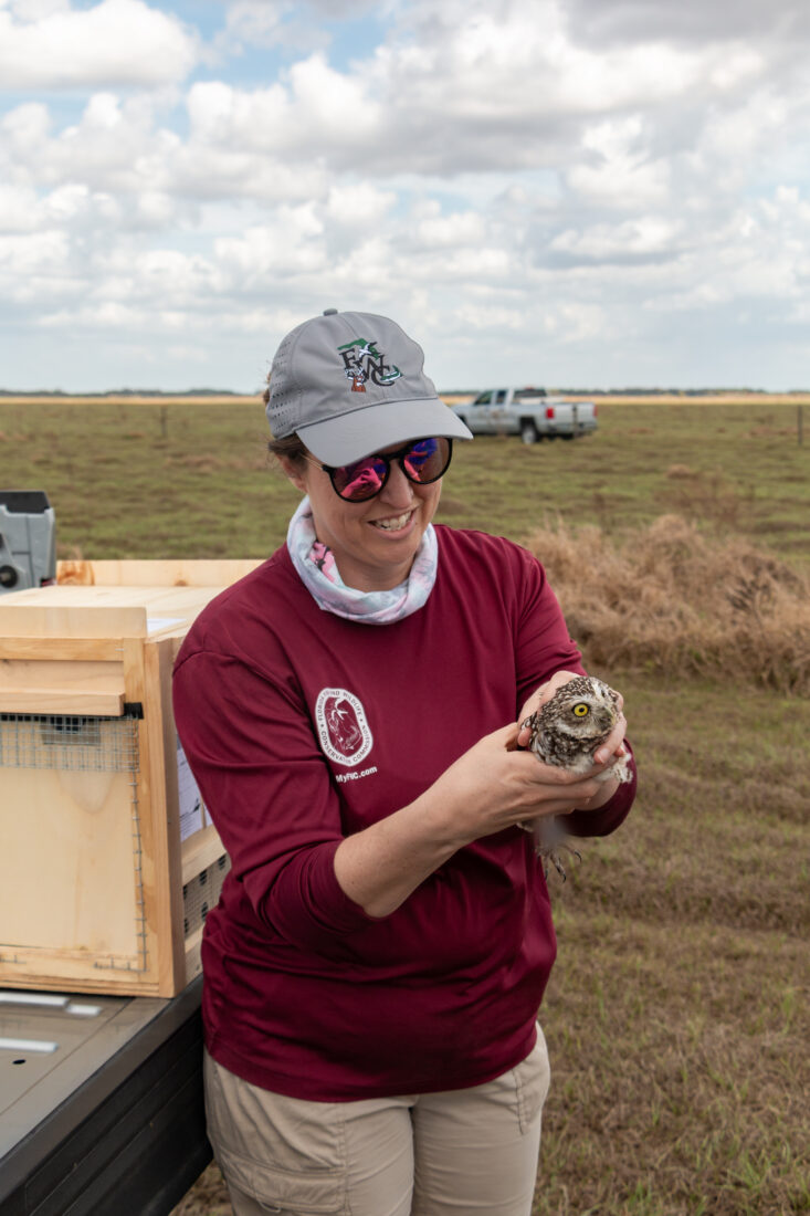 A woman holds a burrowing owl