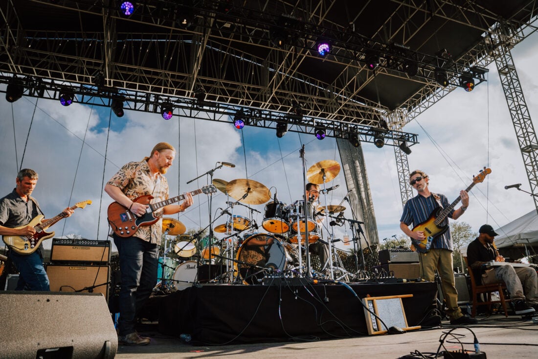 image of band on stage with blue sky background