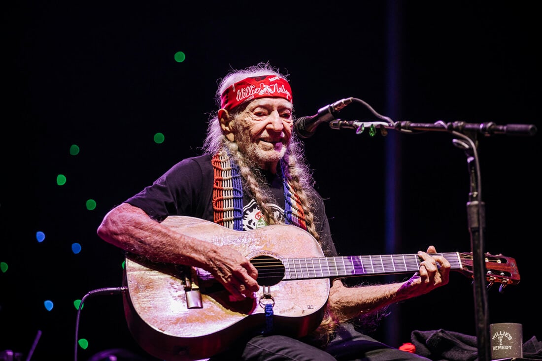 image of Willie Nelson with his guitar on stage