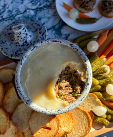 A bowl of pulled pork on a board