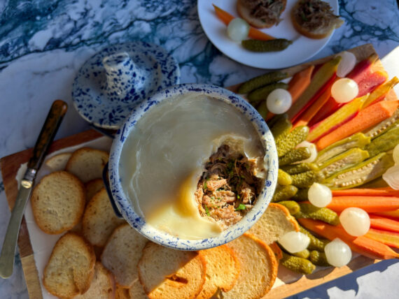 A bowl of pulled pork on a board