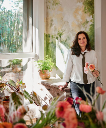 A woman surrounded by flowers in her home