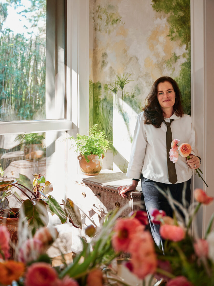 A woman surrounded by flowers in her home