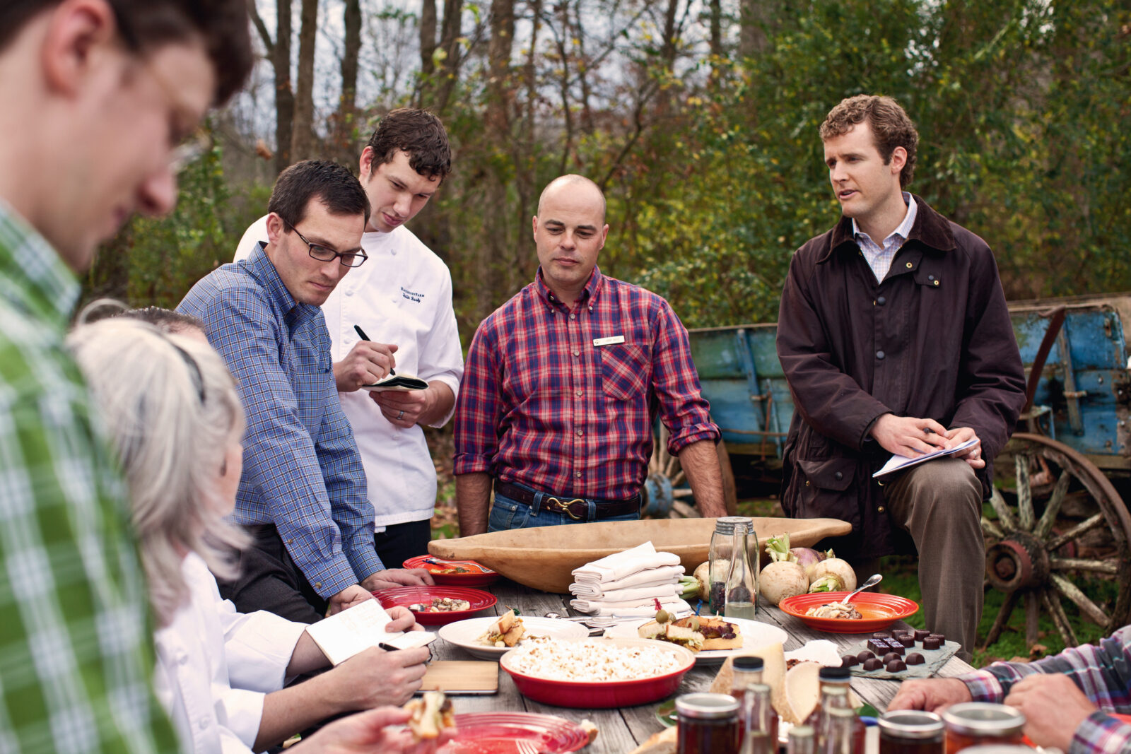 People gather around a table with foods in a garden